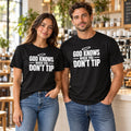 Man and woman in a cafe wearing black Chef Diablo God Knows When You Don't Tip t-shirts